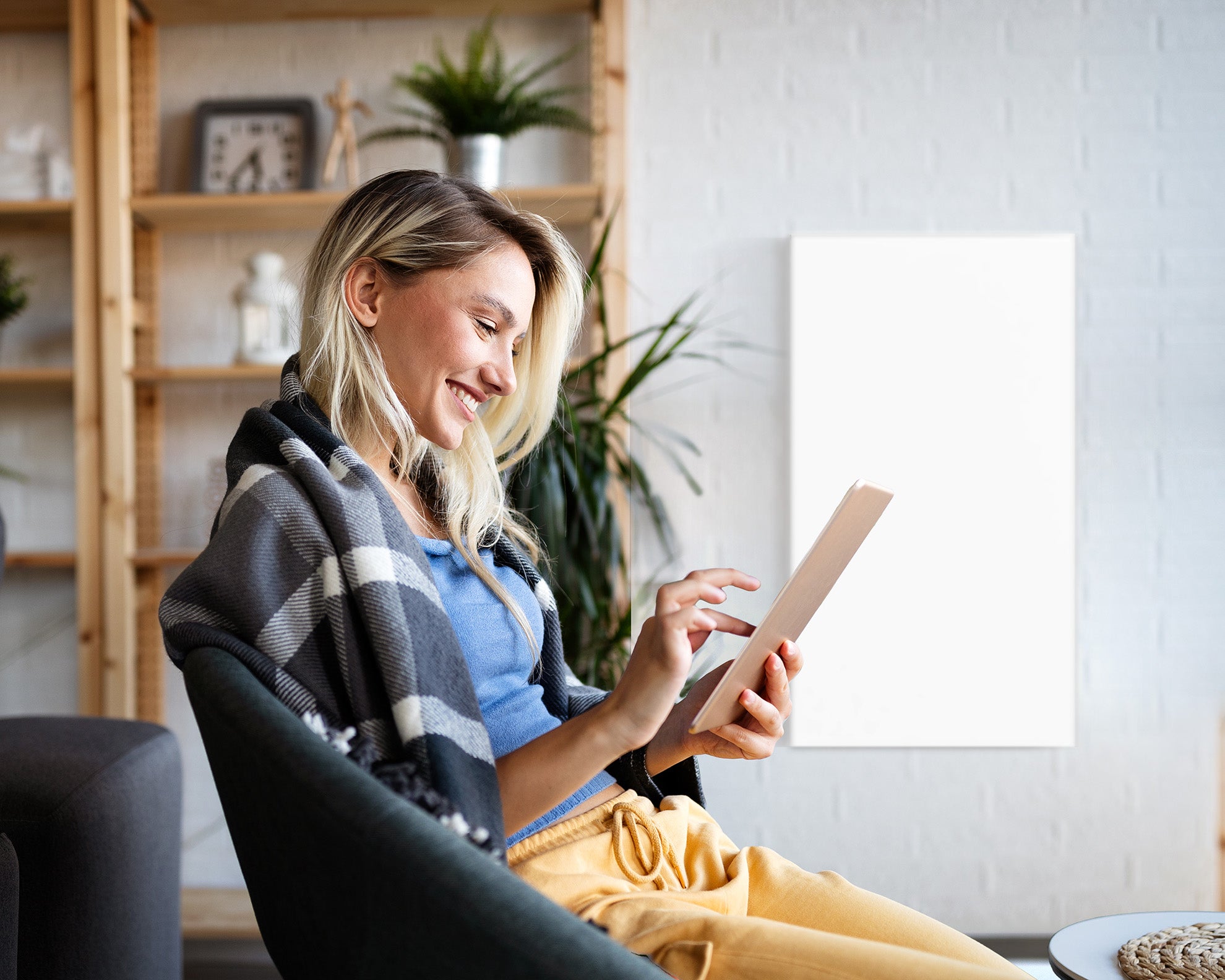 Wohlfühlen und wärem geniesen, junge Frau liest vom Tablett im Hintergrund ist ein Infraredly Paneel Medium an der Wand montiert.
