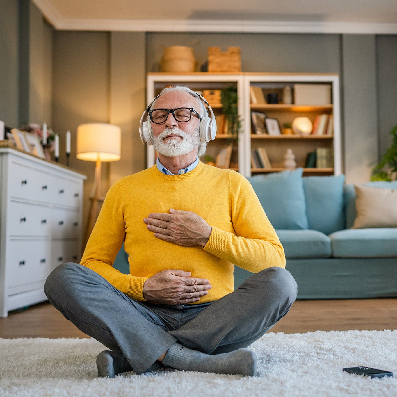 Mann beim Yoga ausüben im Wohnzimmer in wohliger Wohnatmosphäre