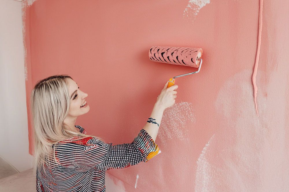 Frau renoviert und streicht die Mauer vor Montage von Infraredly